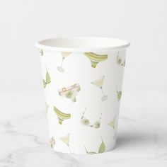 a paper cup filled with drinks on top of a marble countertop next to a white wall