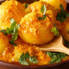 some food that is in a bowl with a wooden spoon on the side and garnished with parsley