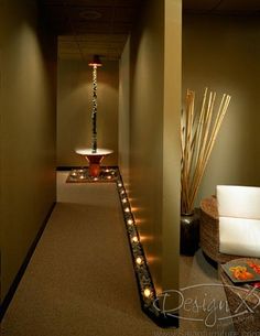 a long hallway leading to a spa with candles on the floor and lights in the walls