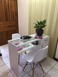 a white desk with two chairs and a potted plant on top of it in front of a wooden door