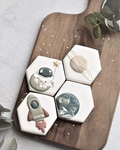 four ceramic coasters sitting on top of a wooden cutting board next to a potted plant