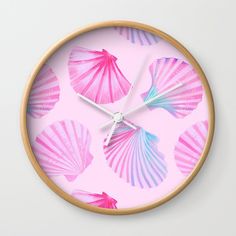 a clock with pink and blue seashells painted on it's face in front of a light pink background