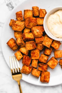 a white plate topped with tater tots next to a bowl of ranch dressing