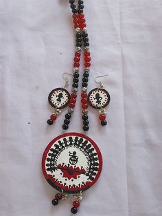 a red and black beaded necklace with two matching earrings on white fabric background,