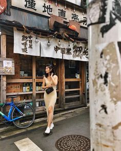 a woman is standing on the street talking on her cell phone