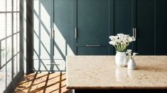 some white flowers are in vases on a table with dark green walls and windows