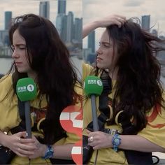 two women with microphones standing next to each other in front of a city skyline