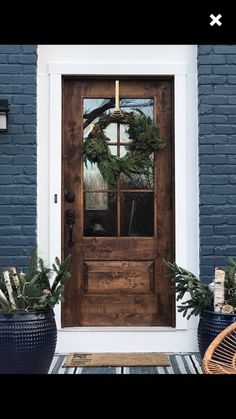 the front door is decorated with wreaths and potted plants