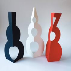 three different colored paper sculptures sitting next to each other