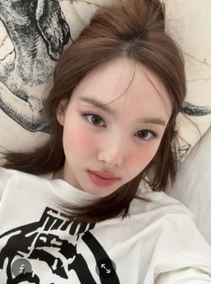 a young woman laying on top of a bed next to a white comforter and pillows