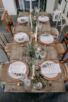 a wooden table topped with plates and place settings