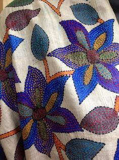 an embroidered fabric with flowers and leaves on it