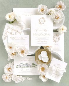 the wedding stationery is laid out on top of each other, with white flowers