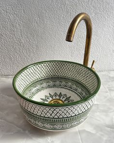 a green and white bowl sink with a brass faucet in the middle on a marble countertop