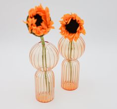 two clear vases with orange flowers in them