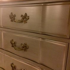 a white dresser with gold handles and drawers