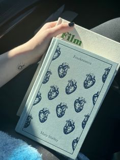 a person is holding a book in their hand while sitting in a car seat with the sun shining on them