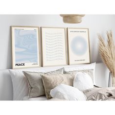 two framed art prints on the wall above a bed with pillows and blankets, next to a plant