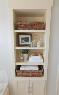 a bathroom with white cabinets and baskets on the shelves