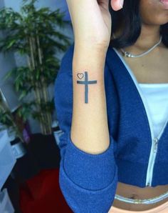 a woman with a small cross tattoo on her left arm, and a heart in the middle