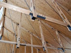 the inside of a building that is being constructed with wooden beams and metal bars hanging from the ceiling