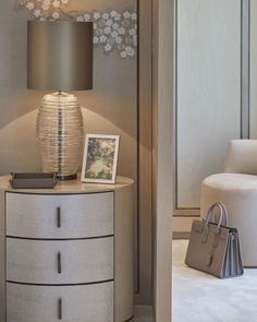 a room with a lamp, chair and pictures on the side table in front of it