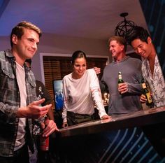 three men and one woman standing at a bar