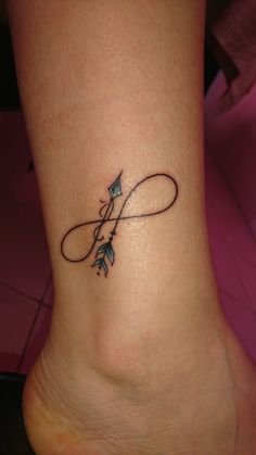 a small tattoo on the ankle of a woman's foot with an arrow in it