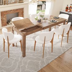 a dining room table with white chairs and a fire place in the backround