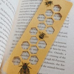 two bees sitting on top of a book next to an open book with the pages cut out