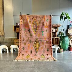 an old rug is hanging on the wall in a room with chairs and other furniture