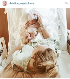 a woman laying on top of a bed holding a baby