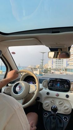 a man driving a car down a street next to the ocean