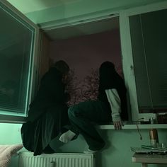 two people are standing on the window sill