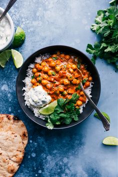 a bowl filled with chickpeas and rice next to pita bread on a blue surface