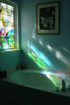 a bath tub sitting under a window next to a painting