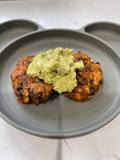 two chicken patties with guacamole on a gray plate, ready to be eaten