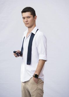 a young man wearing a white shirt and tie holding a cell phone in his right hand