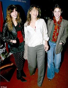 three young women standing next to each other on a red carpeted area with a sign in the background