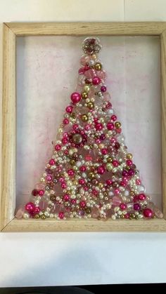 a christmas tree made out of beads in a wooden frame