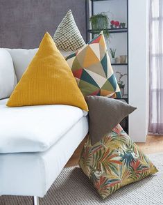 several pillows on a white couch in a living room