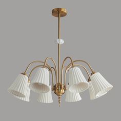 a brass chandelier with five white shades