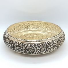 an ornate silver and gold bowl with filigrees on the rim is shown