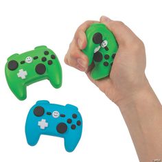 two green and one blue video game controllers in the palm of someone's hand