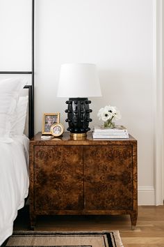 a nightstand with a lamp and pictures on it