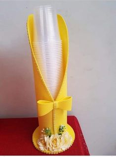 a yellow vase sitting on top of a table with flowers and ribbon around the base