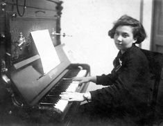 an old black and white photo of a woman sitting at a piano