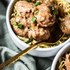 two bowls filled with meatballs and noodles on top of a blue towel next to a fork