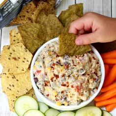 a plate with crackers, carrots, cucumbers and dip on it