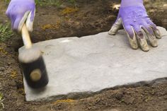 a person wearing purple gloves and gardening gloves is digging in the ground with a shovel